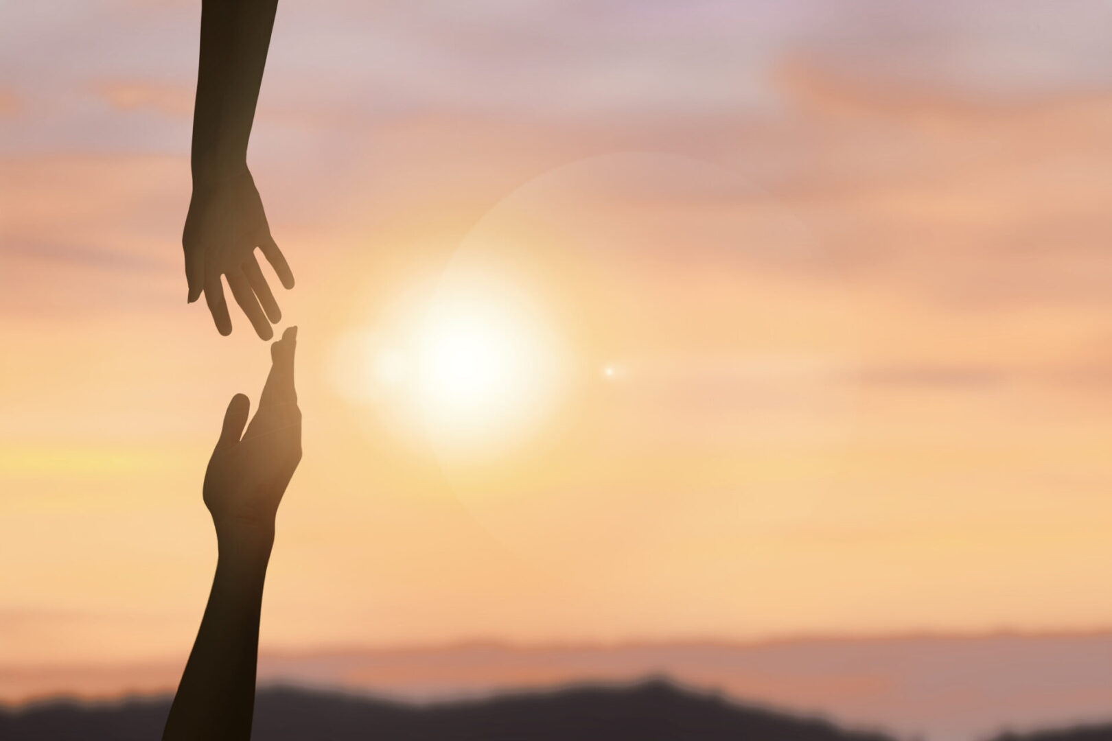 Hands reaching out at sunset sky.